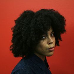 Portrait of woman with curly hair against red background