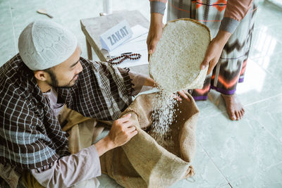 Man pouring rice in sack at mosque