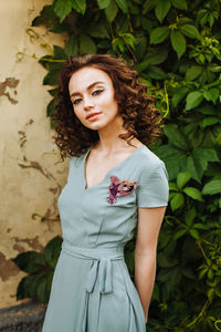 Portrait of young woman wearing make-up while standing against plants