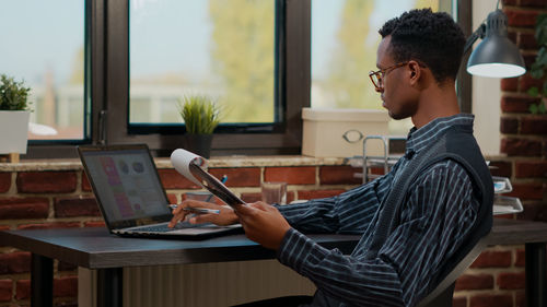 Side view of young businessman using laptop at office