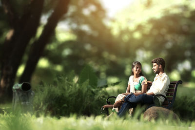 Woman sitting on grass against trees