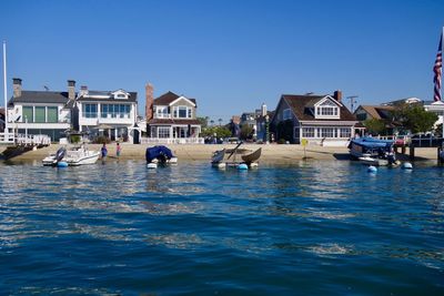 Boats moored by houses against clear blue sky