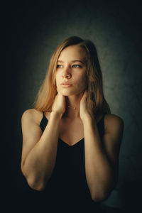 Portrait of young woman against black background