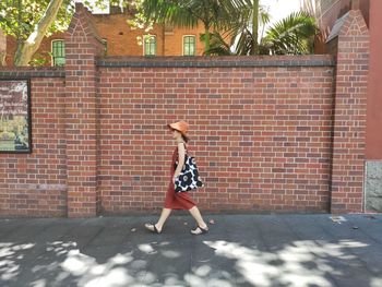 Full length of woman standing against brick wall