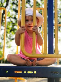 Portrait of cute girl sitting on slide at playground