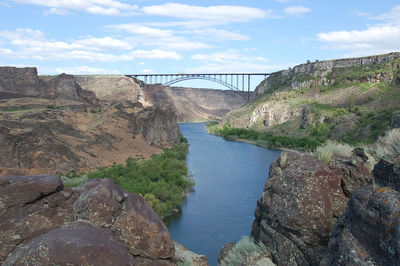 Bridge over river against cloudy sky