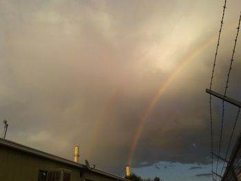 Low angle view of rainbow over buildings against sky