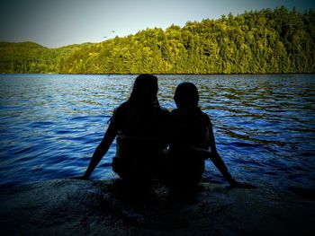 Men in lake against sky