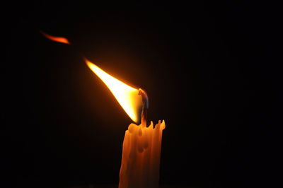 Close-up of lit candle against black background