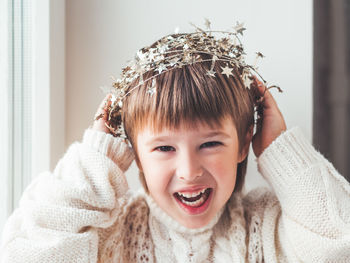 Kid with decorative star tinsel for christmas tree. boy in cable-knit oversized sweater. new year.