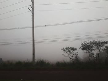 Low angle view of silhouette electricity pylon against sky