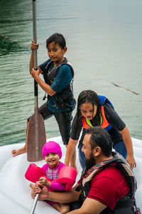 Family wearing life jackets paddling on an inflatable boat in kenyir lake, malaysia.