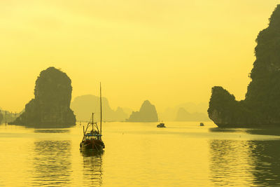 Sailboats in sea against clear sky during sunset