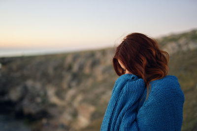 Rear view of woman standing against sky during sunset