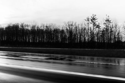 Blurred motion of road by trees against sky