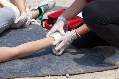 Lifeguards assisting patient lying on blanket