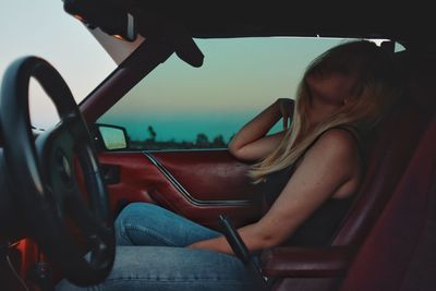 Side view of woman sitting in car