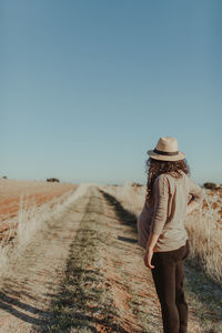 Pregnant woman standing on country road against clear sky