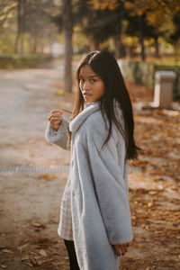 Young woman standing against tree