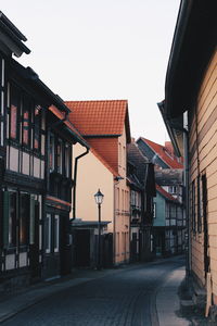 Houses by street in city against clear sky