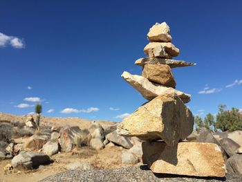 Low angle view of stone stack on rock against sky