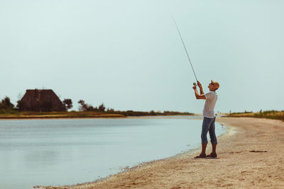 Rear view of woman walking on beach against clear sky