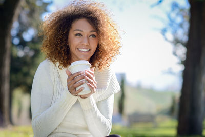 Young woman holding disposable cup on field