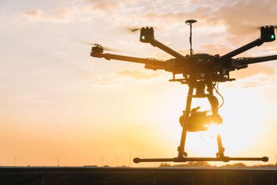 Low angle view of machine part against sky during sunset