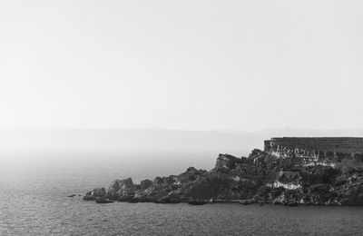 Rock formation by sea against sky