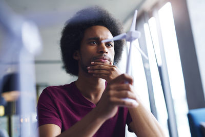 Young man looking at windmill model in office