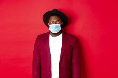 Portrait of young man standing against red background