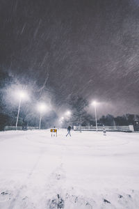Snow covered field against sky at night