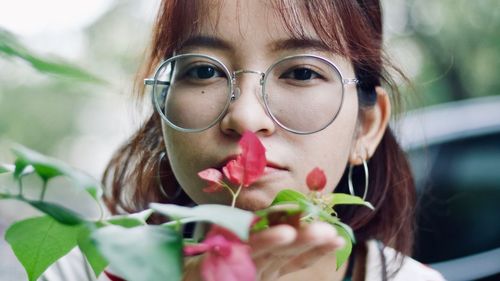 Close-up portrait of young woman with leaves outdoors