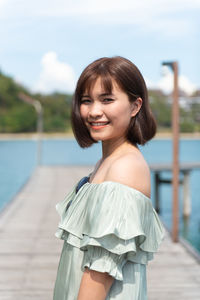 Portrait of smiling woman standing against water