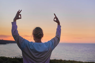 Attractive woman meditating and performing yoga breaths at sunset. no recognizable face