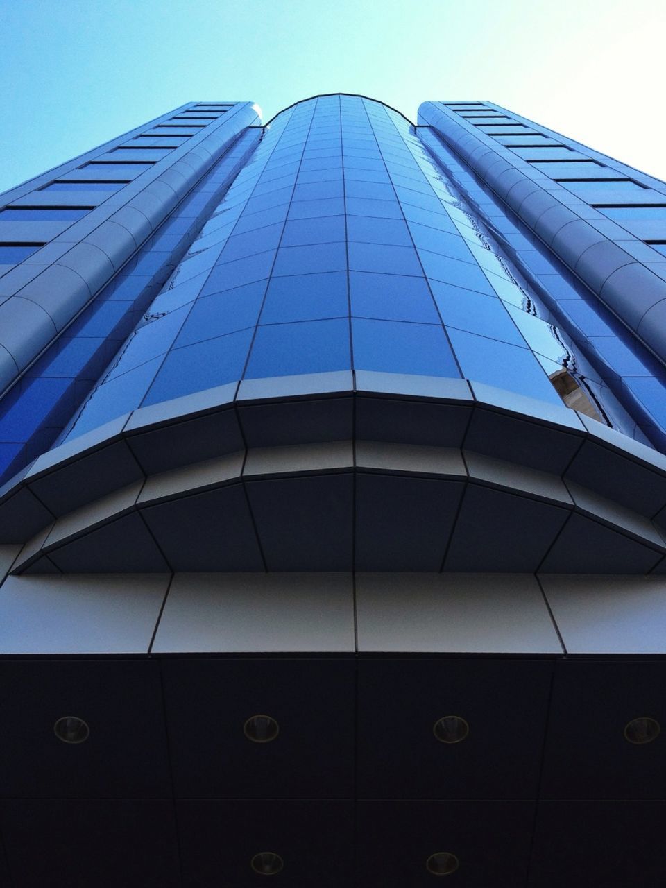 low angle view, architecture, modern, building exterior, built structure, office building, skyscraper, glass - material, tall - high, city, reflection, tower, building, sky, clear sky, glass, day, window, no people, tall