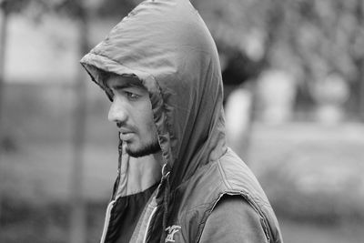 Side view of man wearing hooded jacket while looking away