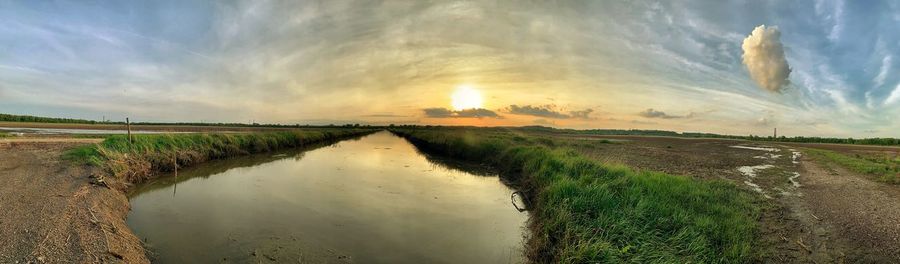 Panoramic shot of agricultural field against sky during sunset