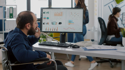 Side view of man using laptop at office