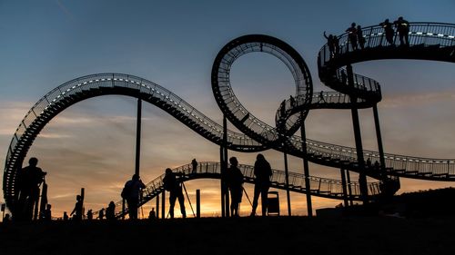 Silhouette of people with ferris wheel against sky