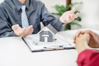 Midsection of real estate agent and colleague working at desk in office