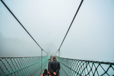 Rear view of people on bridge against sky