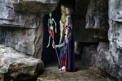 Portrait of cute girl wearing costume standing against rock formation