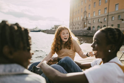 Shocked teenage girl enjoying with friends near lake at sunny day