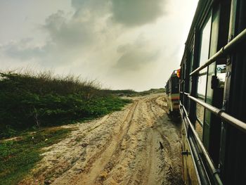 Train on railroad track amidst field against sky