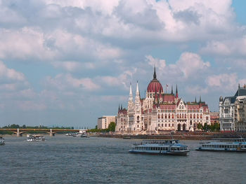 Buildings at waterfront against cloudy sky