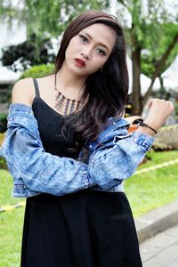 Portrait of beautiful young woman standing on footpath