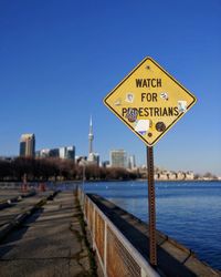 Information sign by road against clear blue sky