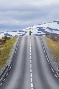 Rear view of man skateboarding on road against sky