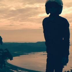 Silhouette man looking at sea against sky during sunset